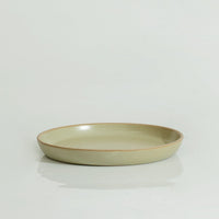 An olive green round stoneware plate with a swirl pattern on a white background.