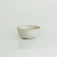 A white ceramic cereal bowl with a swirl pattern on the inside, displayed against a neutral background.