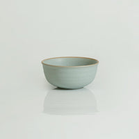 A set of blue stoneware bowls and plates with a swirl pattern, displayed on a table with a white vase and a blue napkin.